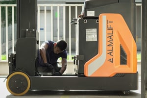 Técnico realizando mantenimiento en una carretilla elevadora Almalift dentro de un área logística.